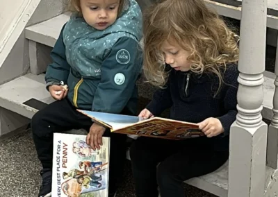 Two young children sitting on a staircase reading picture books