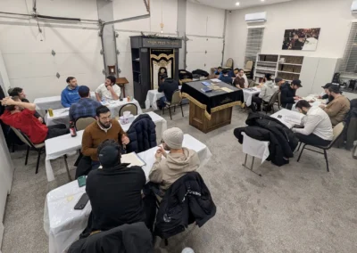 Men studying in pairs at tables around a velvet-covered bimah