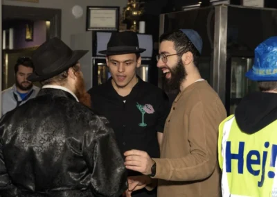 Men in costumes laughing together, one wearing a high-visibility vest that reads “Hej!”
